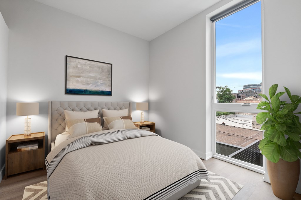 a bedroom with a large window and a bed with a tufted headboard