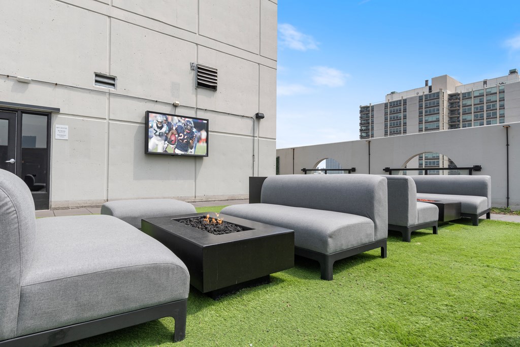A rooftop lounge with couches and a fire pit and the mounted TV at 1250 LaSalle