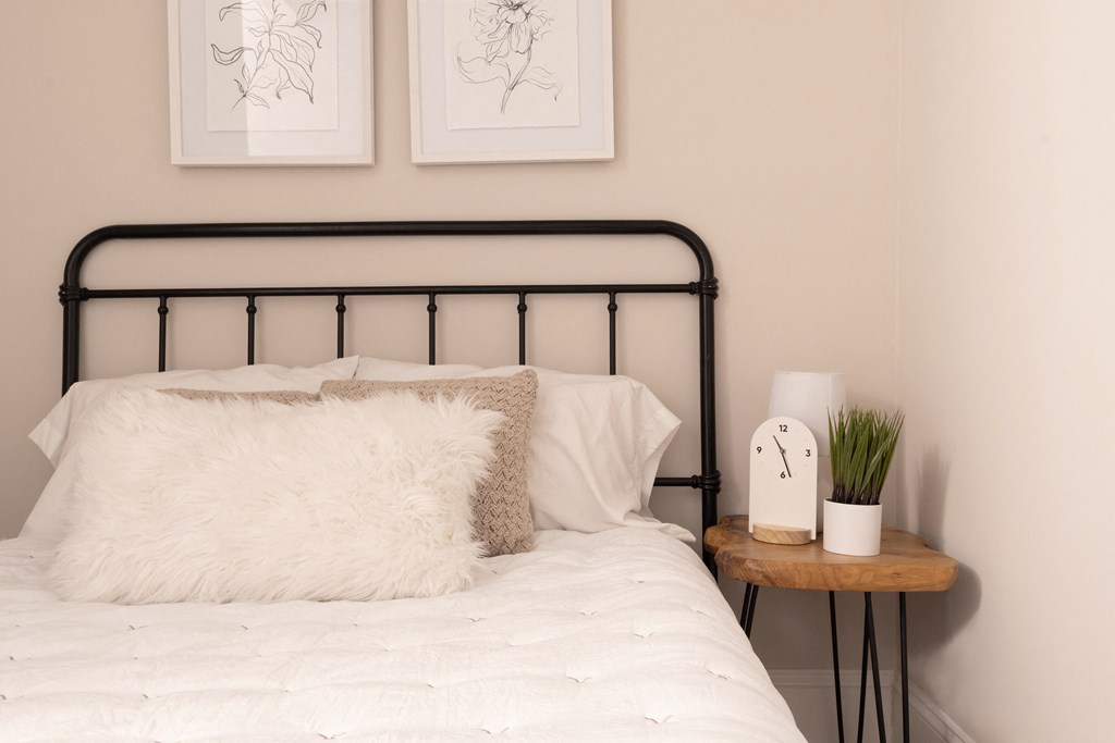 a bedroom with a bed with a white comforter and pillows and pictures