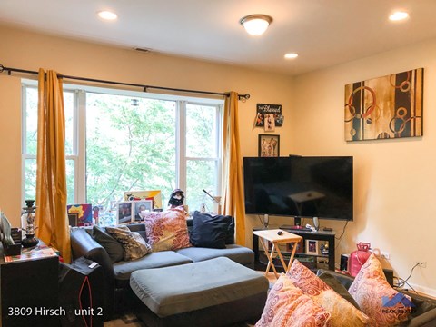 A living room with a grey couch and a television on the wall.