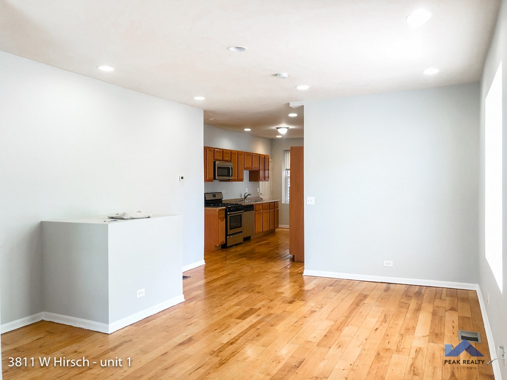an empty living room and kitchen with white walls and wood floors