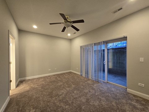 A room with a ceiling fan and carpeted floor.