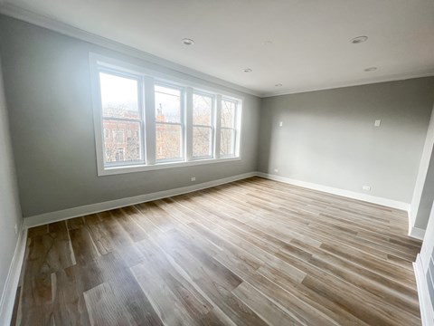 A room with wooden flooring and a window overlooking a cityscape.