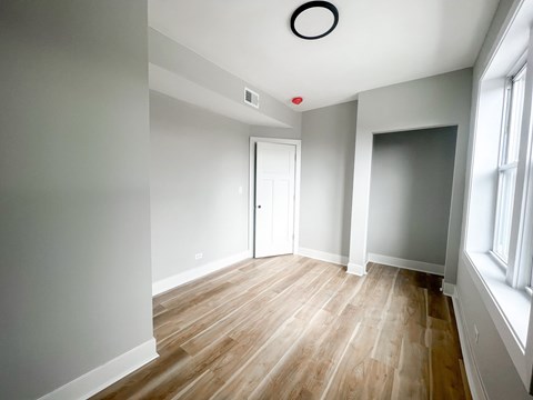 A room with a white door and a window on the right side.