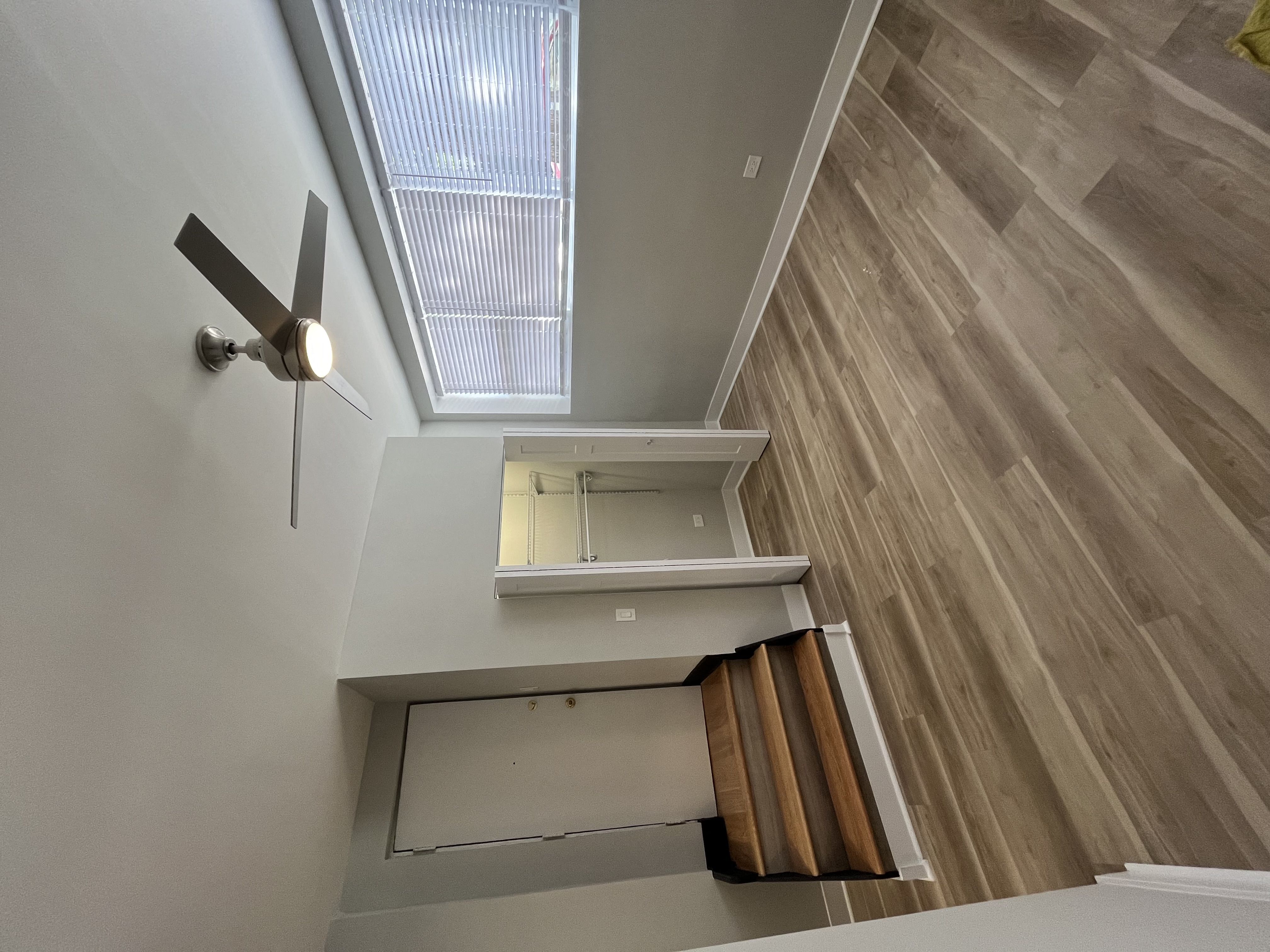 a ceiling fan and a window in a room with a staircase