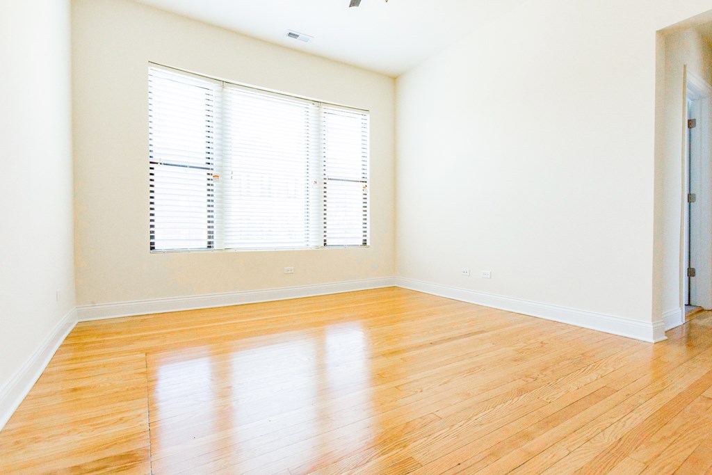 an empty living room with wood floors and a window