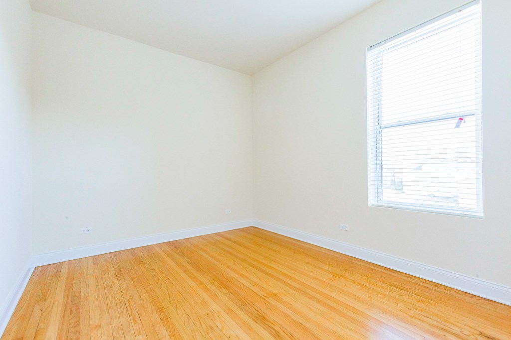 an empty room with wood floors and a window