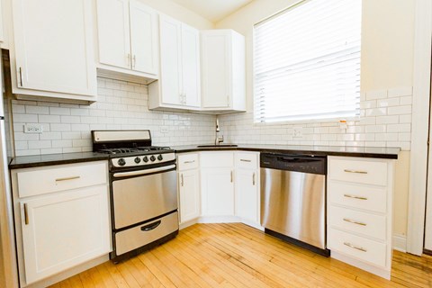 a white kitchen with stainless steel appliances and white cabinets