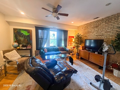 a living room with leather furniture and a ceiling fan