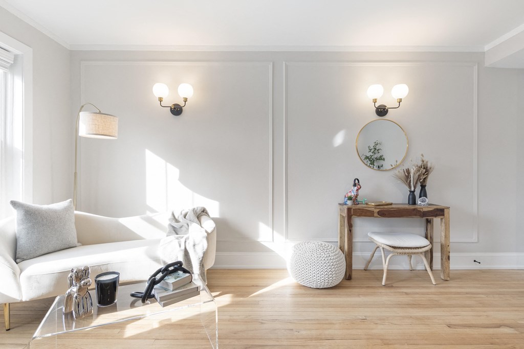 a living room with white walls and a white couch and a table with a mirror