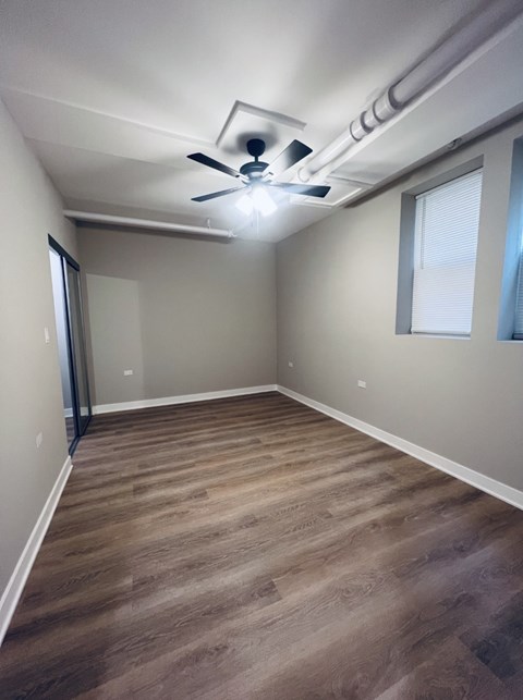 A room with a ceiling fan and wooden flooring.