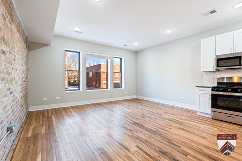 A spacious apartment with a brick wall and wooden flooring.