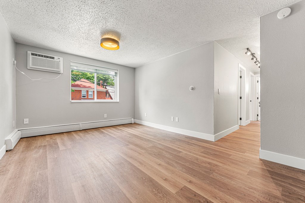 an empty room with hardwood floors and a large window