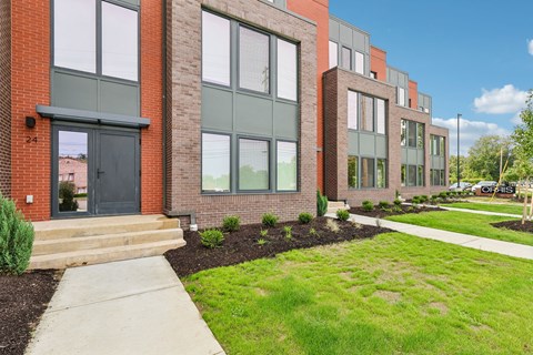 A row of modern brick houses with green lawns in front.