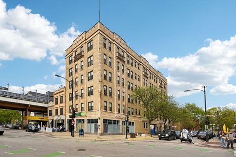 A large tan building with a flat roof and a street in front of it.