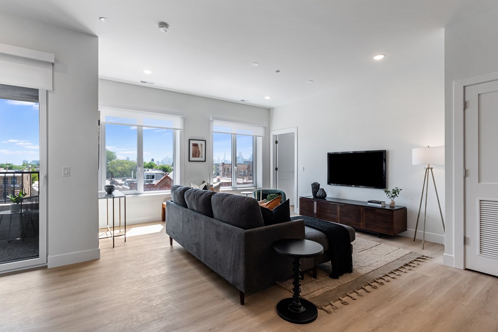A modern living room with a grey couch and a black stool.