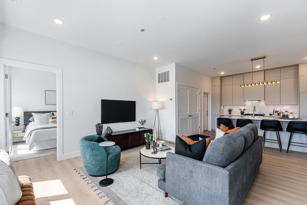 A modern living room with a grey sofa, a blue armchair, and a television.