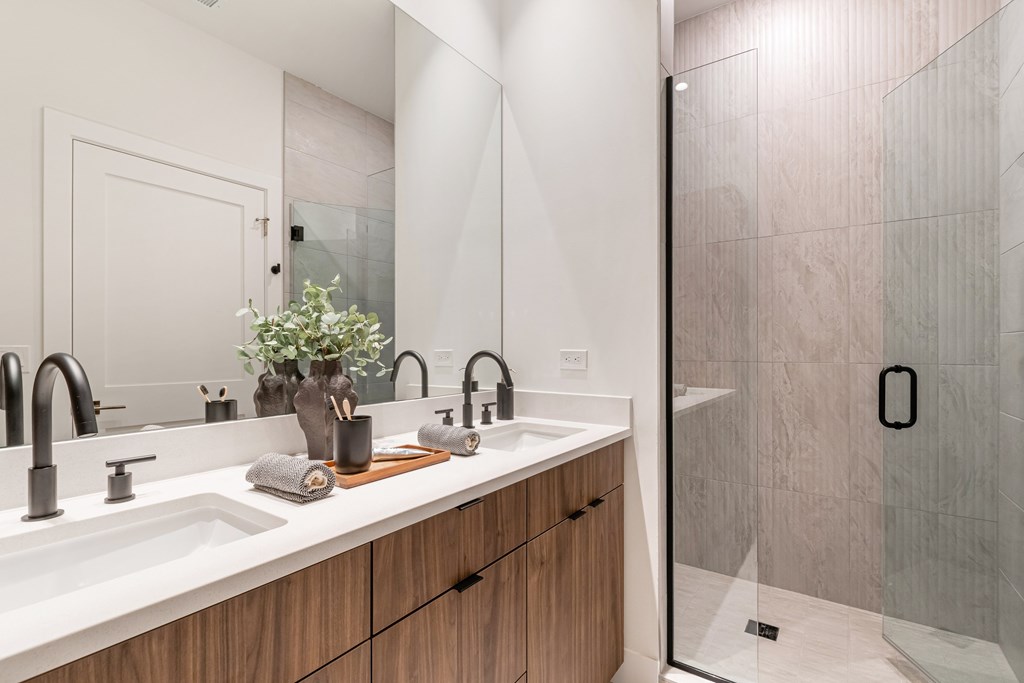 A modern bathroom with a wooden vanity and a glass shower.