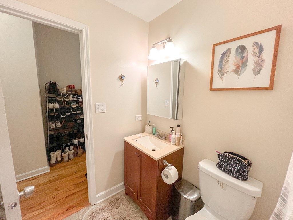 a bathroom with a toilet sink and mirror and a closet