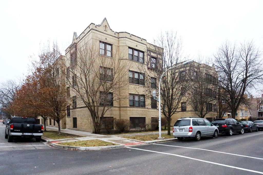 an apartment building with cars parked in a parking lot