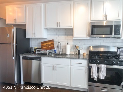 A kitchen with white cabinets and a black refrigerator.