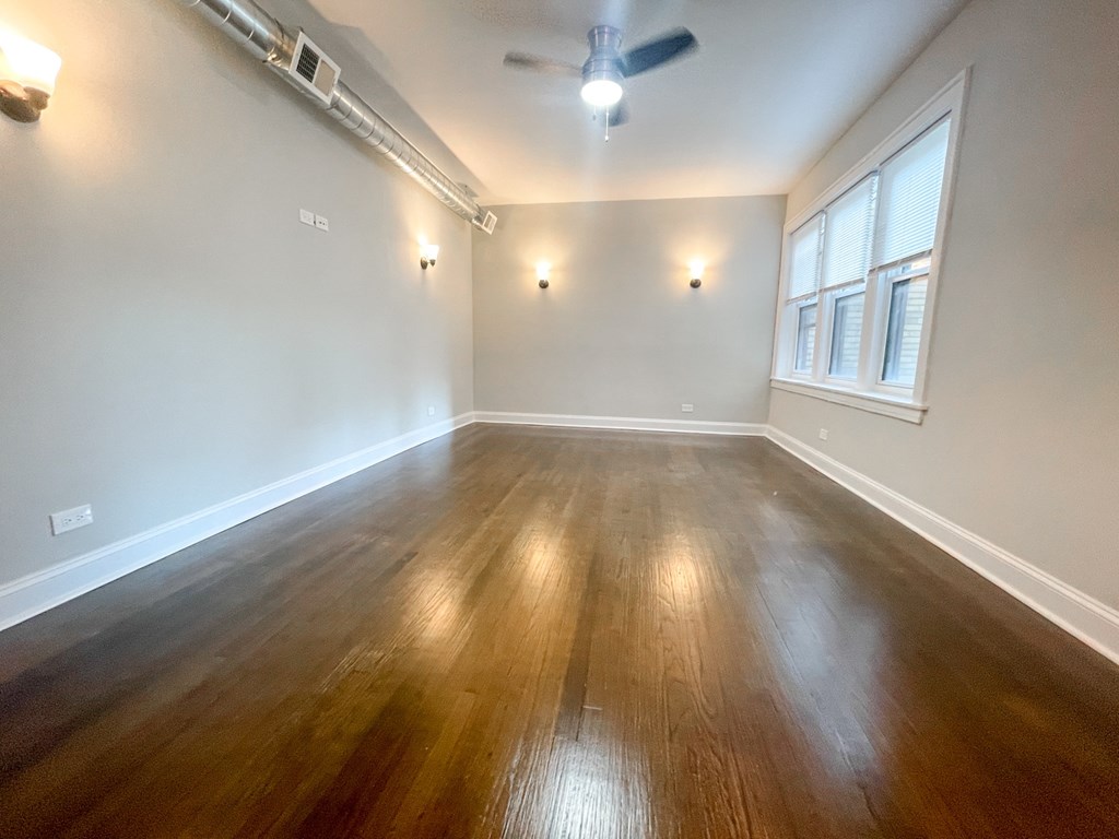 A room with wooden flooring and a ceiling fan.