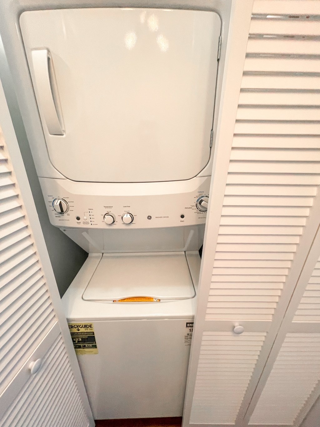 A white washing machine is sitting in a small space.