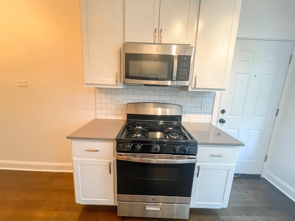 A kitchen with a stove top oven and microwave above it.