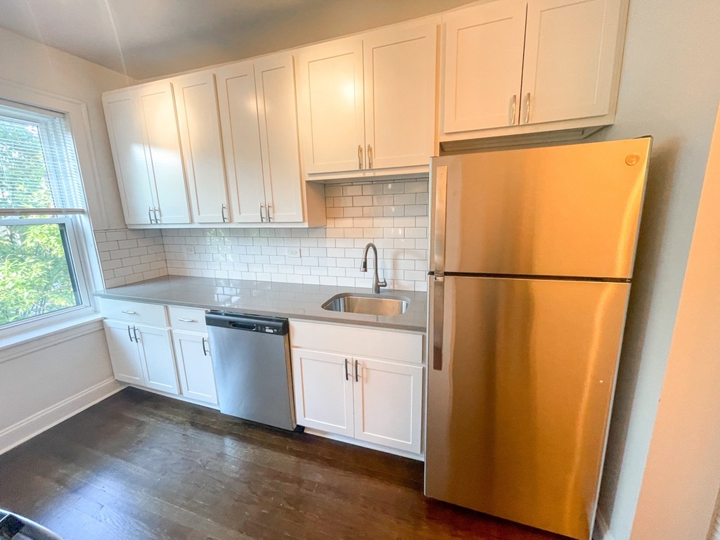 A kitchen with white cabinets and a stainless steel refrigerator.