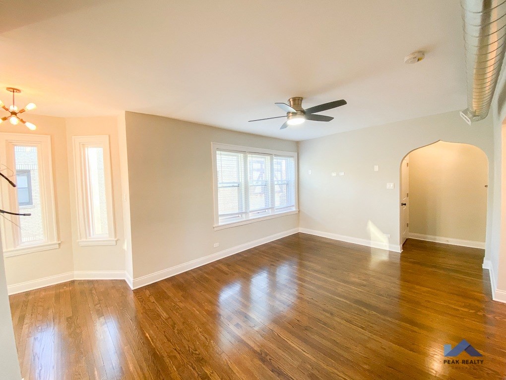 an empty living room with hardwood floors and a ceiling fan