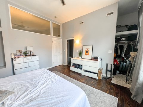 A bedroom with a large bed and a white dresser.