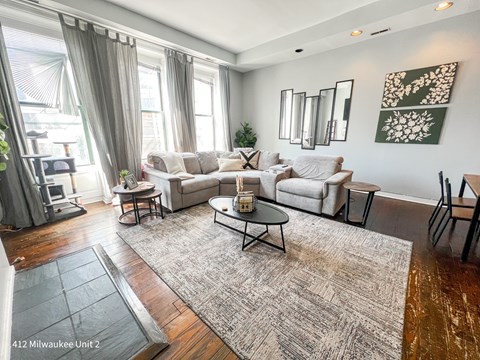 A living room with a grey rug and white furniture.