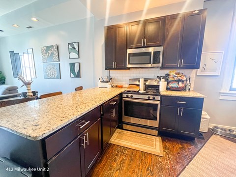 A kitchen with black cabinets and a granite countertop.