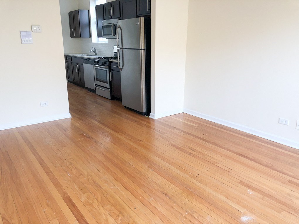 a kitchen and living room with wood floors and a refrigerator