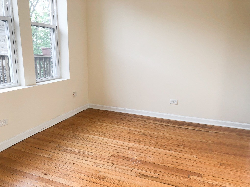 an empty room with wooden flooring and two windows