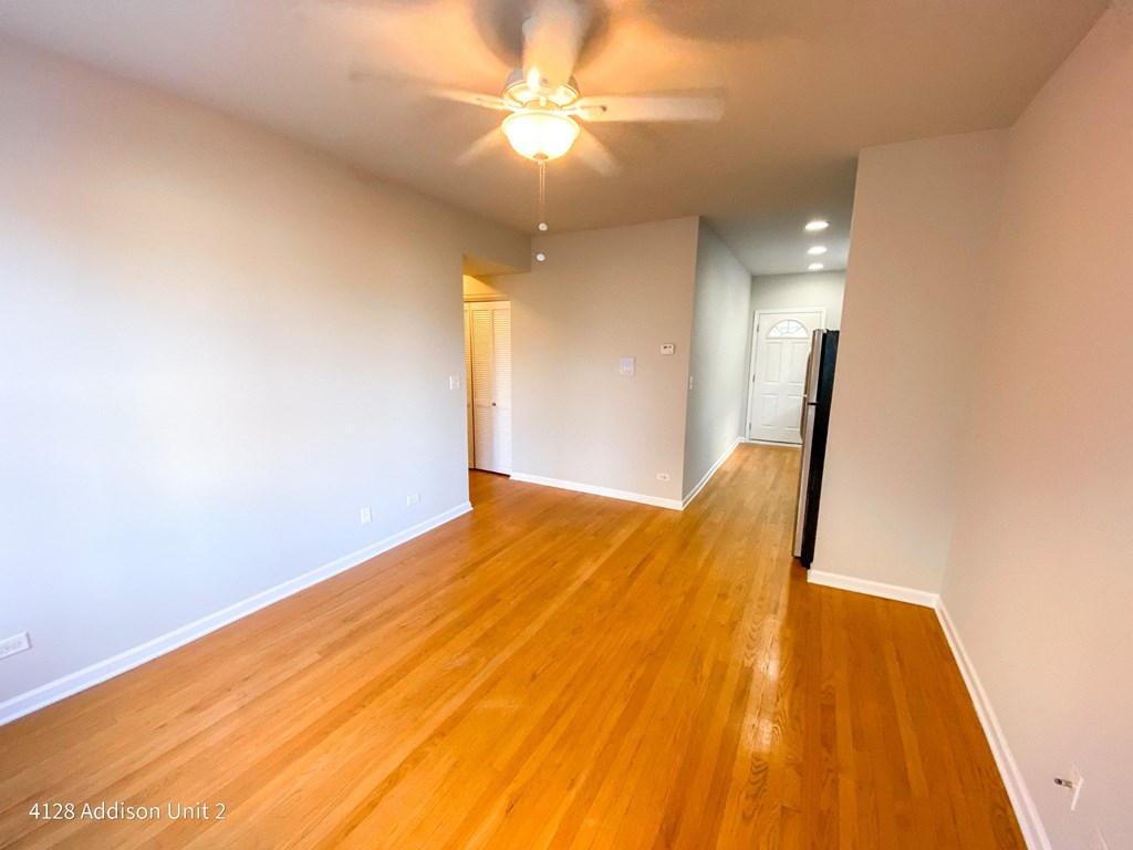 an empty living room with wood floors and a ceiling fan