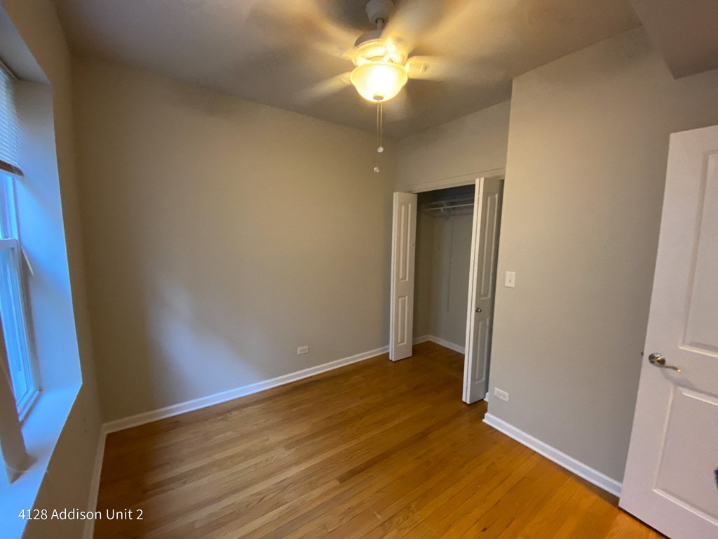 an empty living room with wood floors and a ceiling fan