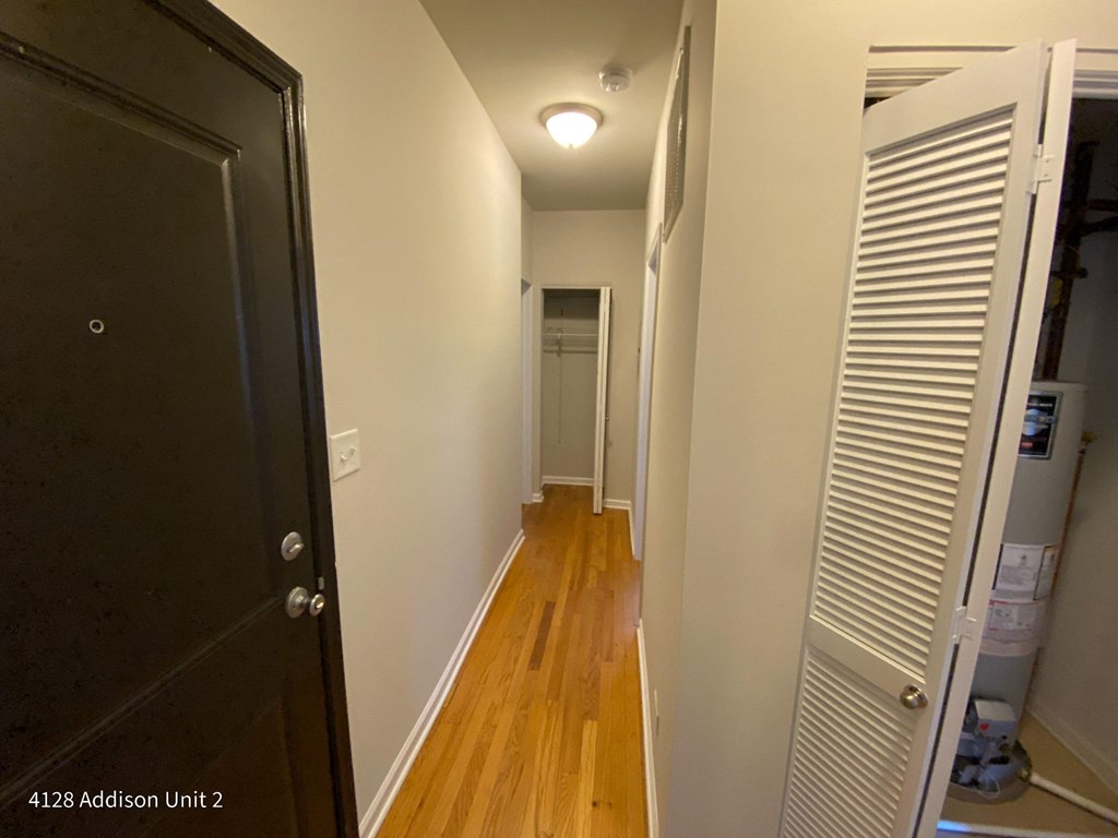 a small hallway with a closet and a door to a hallway with wood flooring