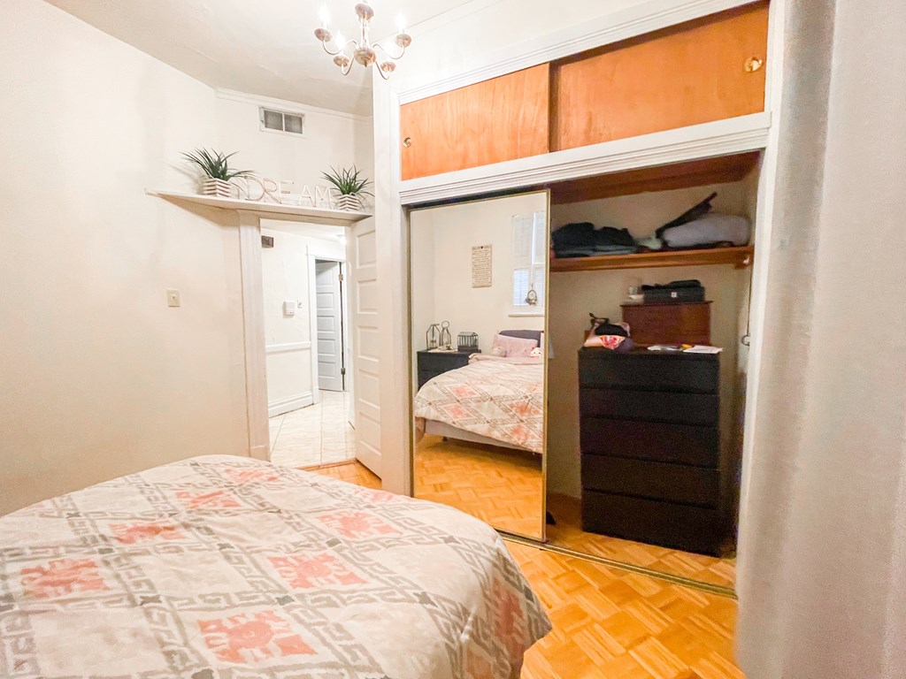 A bedroom with a bed, a dresser, and a small closet.