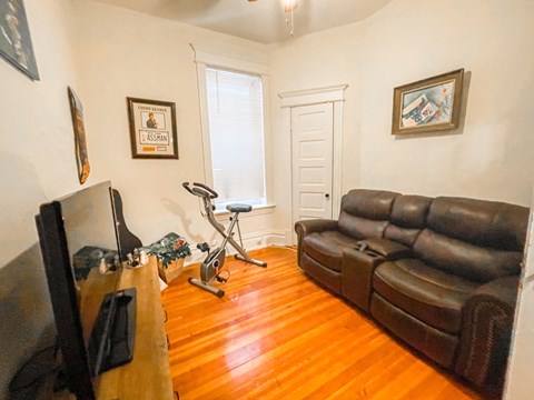 A living room with a brown leather couch and a stationary bike.