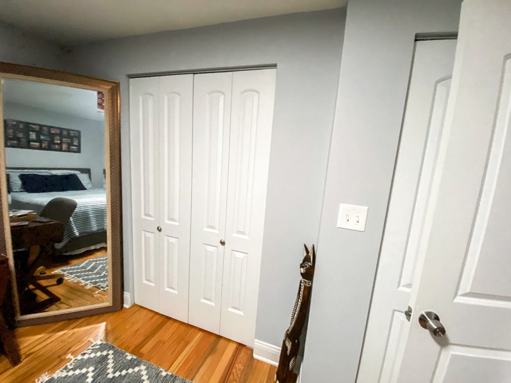 A room with a white door and a mirror on the wall.