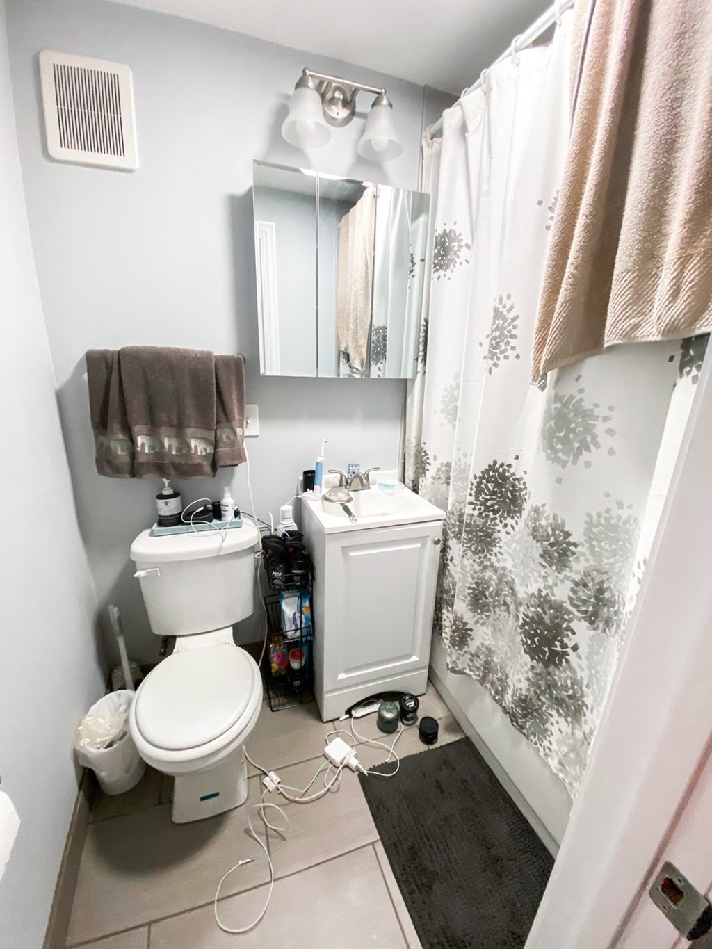 A white toilet with a white cabinet and a mirror above it.