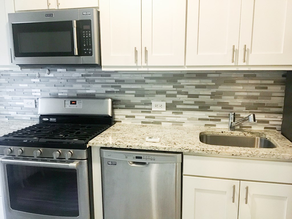 A kitchen with a stove, dishwasher, and microwave.
