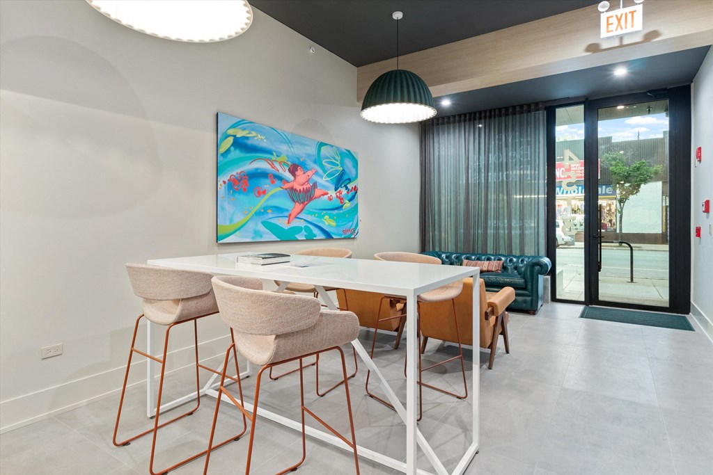 a dining area with a table and chairs and a painting on the wall