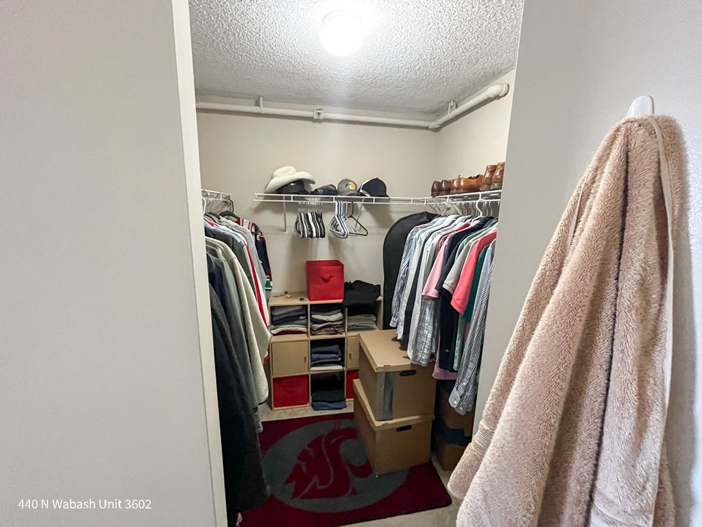 a walk in closet with a rack of clothes and a red chair