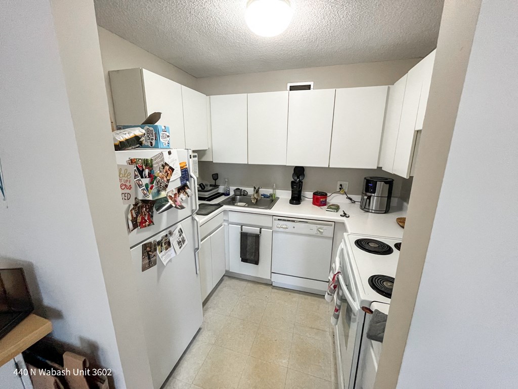 a kitchen with white cabinets and appliances and a refrigerator and a stove