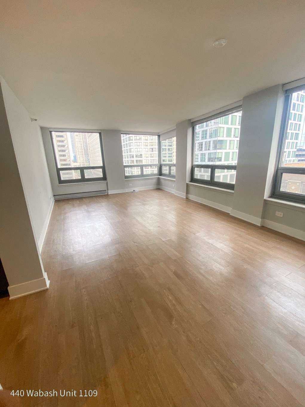 an empty living room with hardwood floors and large windows