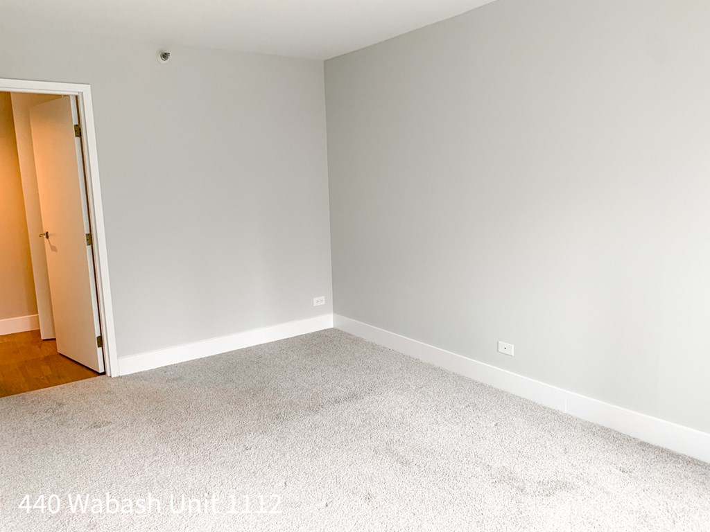 an empty room with white carpet and a door