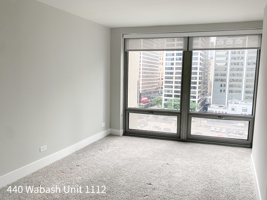 a bedroom with a large window and a carpeted floor