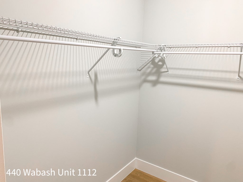 a walk in closet with white walls and hanging racks